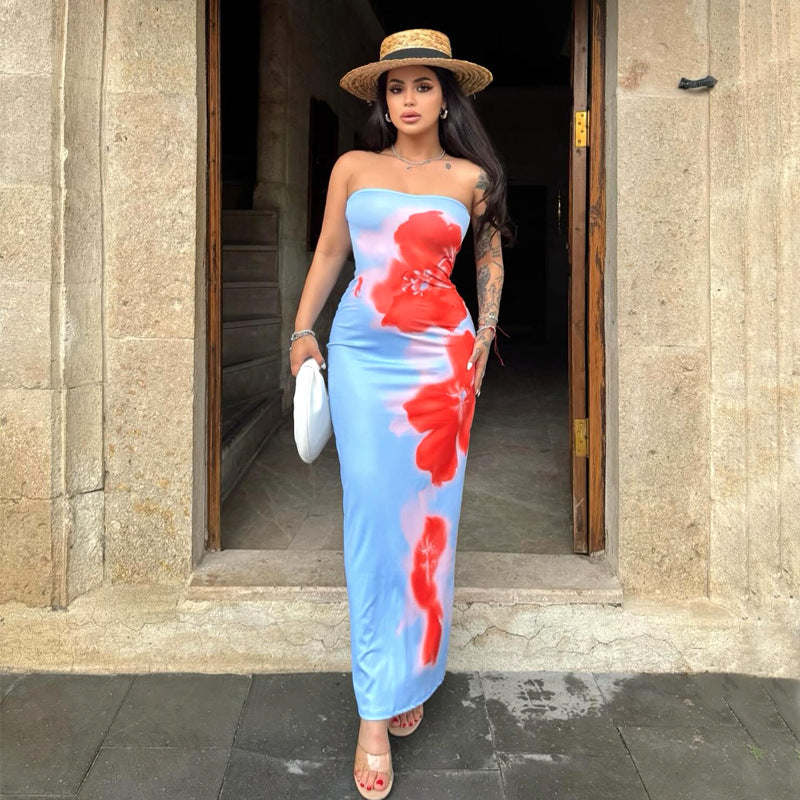 Woman wearing a vibrant tube top floral print maxi dress with high waist and side slit, glowing at a summer festival with bold accessories.