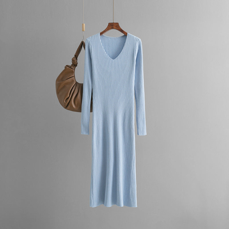 Model poses in a bold autumn-winter V neck knitted sweater dress with sunken stripes, high side slit, and layered festival-ready accessories at night.