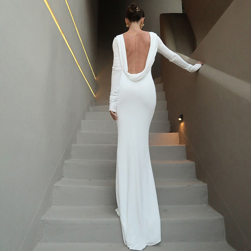 Bold partygoer in a solid color backless chain dress with long sleeves, exuding confidence and style amid vibrant festival lights and nightlife energy.