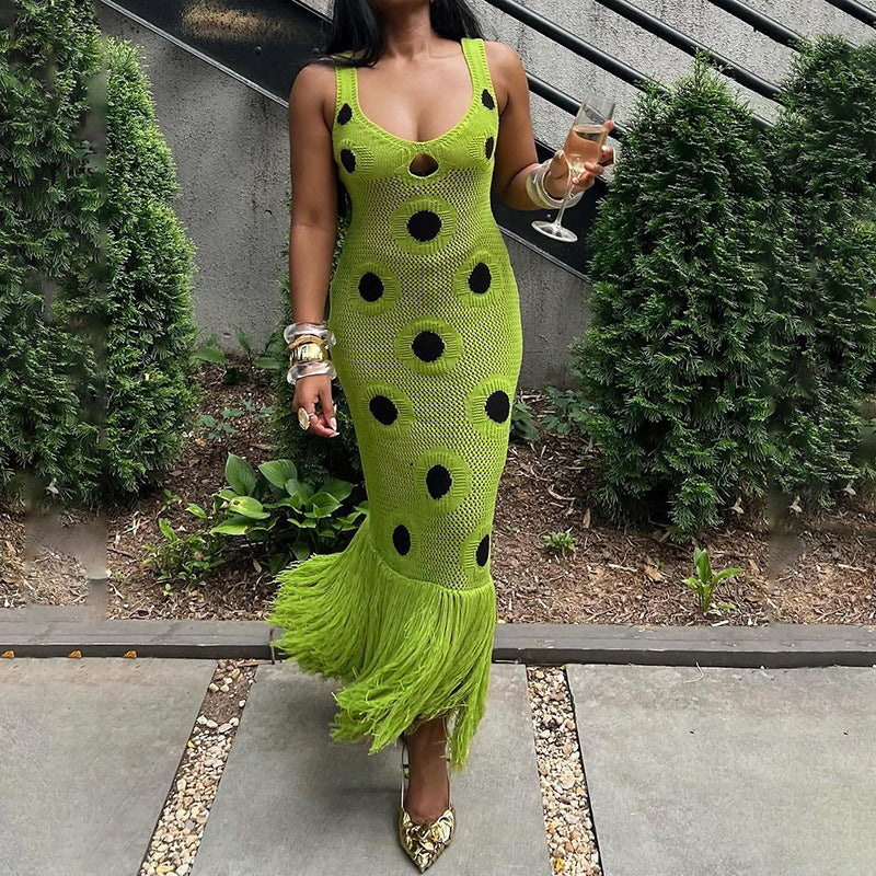 Woman wearing black knit polka dot dress with tassel hem, dancing confidently at a vibrant autumn festival. Edgy, playful, bold nightlife style.