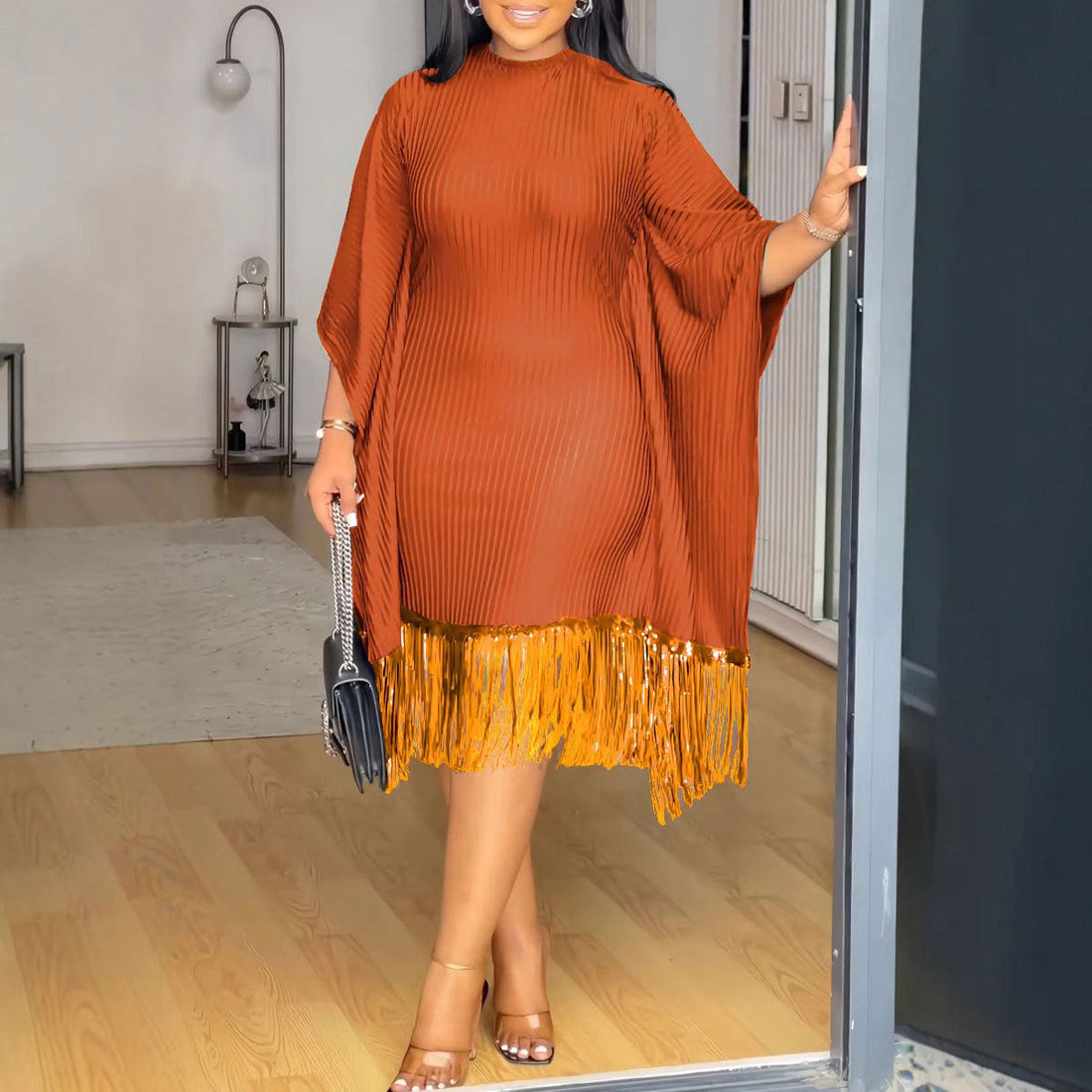 Woman in a sequined tassel bat sleeve elastic hip dress, radiating confidence at an evening event with shimmering fabric and bold, fluid movement.